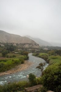 A tranquil river flows through a lush valley amidst mountainous terrain in Lima, Peru.